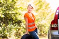 Young female driver wearing a high visibility vest, calling the roadside service Royalty Free Stock Photo