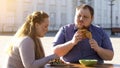 Young female eating vegetable salad, man chewing fried chicken, diet choice