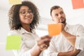 Young female employee attaching sticky note during brainstorming with colleague