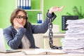 The young female employee busy with ongoing paperwork chained to the desk