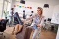 A young female employee enjoys riding a bike during a break in the office. Employees, job, office