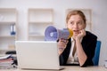 Young female employee holding megaphone in the office Royalty Free Stock Photo