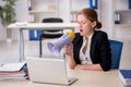 Young female employee holding megaphone in the office Royalty Free Stock Photo