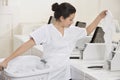 Young female employee putting clothes in washing machine