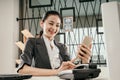 Young female employee sit at office desks looking at smartphone Royalty Free Stock Photo