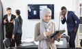 Young female employee stands holding a tablet and is ready for an online meeting for company business. Behind is the atmosphere of Royalty Free Stock Photo