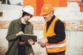 Young female engineer and senior construction worker in hardhat looking at blueprints of new modern house. Stylish woman architect Royalty Free Stock Photo