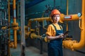 A young female engineer in a uniform and a protective helmet, holding a digital tablet in her hands and conducting an Royalty Free Stock Photo