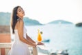 Young female enjoying a colourful cocktail on the panoramic view hotel terrace.Cold delicious cocktail smoothie