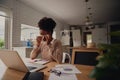 Young female entrepreneur sitting alone blowing nose while using laptop during work from home Royalty Free Stock Photo