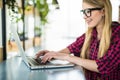 Young female entrepreneur working sitting at a desk typing on her laptop computer in a office, view from side Royalty Free Stock Photo