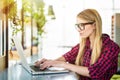 Young female entrepreneur working sitting at a desk typing on her laptop computer in a office, view from side Royalty Free Stock Photo