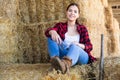 Young female farmer sitting on straw stack on hayloft Royalty Free Stock Photo