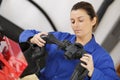 Young female fixing mechanical part in workshop