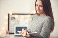 Young woman freelancer indoors home office concept winter atmosphere blurred background writing in planner Royalty Free Stock Photo