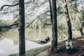 Young female freelancer working on laptop while lying on a hammock near a lake, hipster woman resting in nature near retro italian Royalty Free Stock Photo