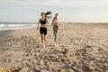 Young female friends in sportswear running on beach in morning sunrise. Outdoor workout routine Royalty Free Stock Photo