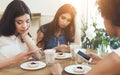 Young female friends using telephones and feel boring together