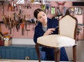 Young female furniture maker working on vintage chair in workshop