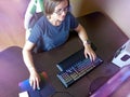 Young female gamer in round glasses playing a computer game. A person plays an online video game using a keyboard