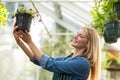 Young female gardener looking at potted flowering plant