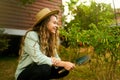 Young female gardener smiles on her farm sitting among plants. Happy cauasian woman in her garden with a scoop near ripe