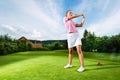 Young female golf player on course doing golf swing Royalty Free Stock Photo