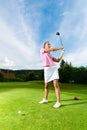 Young female golf player on course doing golf swing Royalty Free Stock Photo