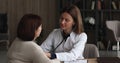 Female doctor holding stethoscope listens heartbeat of older patient