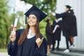 A young female graduate with a scroll background of university graduates. Royalty Free Stock Photo