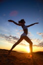 Young female gymnast exercising at sunrise