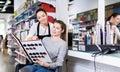 Young female hairdresser with woman client looking samples of hair dye in beauty salon Royalty Free Stock Photo