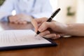 Young female hand holding pen able to sign paper contract