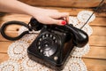 Girl hand holding old telephone headset on lace tablecloths and wooden background Royalty Free Stock Photo