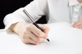 Young female hand will write something on a blank sheet