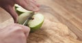 Young female hands cut green apple into quarters Royalty Free Stock Photo