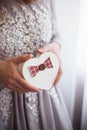 Young female hands holding gift box in form of heart near window in daylight Royalty Free Stock Photo