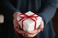 Young female hands holding gift box with red ribbon Royalty Free Stock Photo