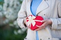 Young female hands holding gift box in shape of red heart with blurred spring background Royalty Free Stock Photo