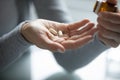 Young female hands holding opened pill bottle and two capsules