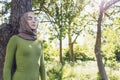 Young female in a hijab and casual clothes in the park. Protecting the environment and caring for plants concept