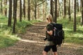 Female hiker with big backpack in green forest