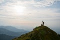 Young female hiker celebrating success on the top of the mountain in the sunset