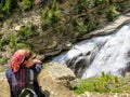 A young female hiker at the edge of the cliff looking down at the rushing waters of Toboggan Falls