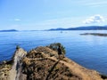 A young female hiker at the end of a path ending at a point overlooking a beautiful blue ocean with islands in the distance