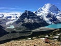 A young female hiker meditating naked overlooking an incredible valley with a huge mountain, glacier, and turquoise lake