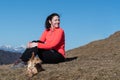 Young female hiker sitting with her dog on hill slope and looking over shoulder Royalty Free Stock Photo