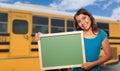 Young Female Hispanic Student with Blank Chalkboard Near School Bus Royalty Free Stock Photo