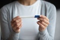 Young female holding midstream rapid pregnancy test looking at result