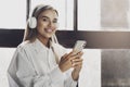 Young female holding smartphone in hands, listening to music in headphones. Audio and video streaming and sharing online Royalty Free Stock Photo